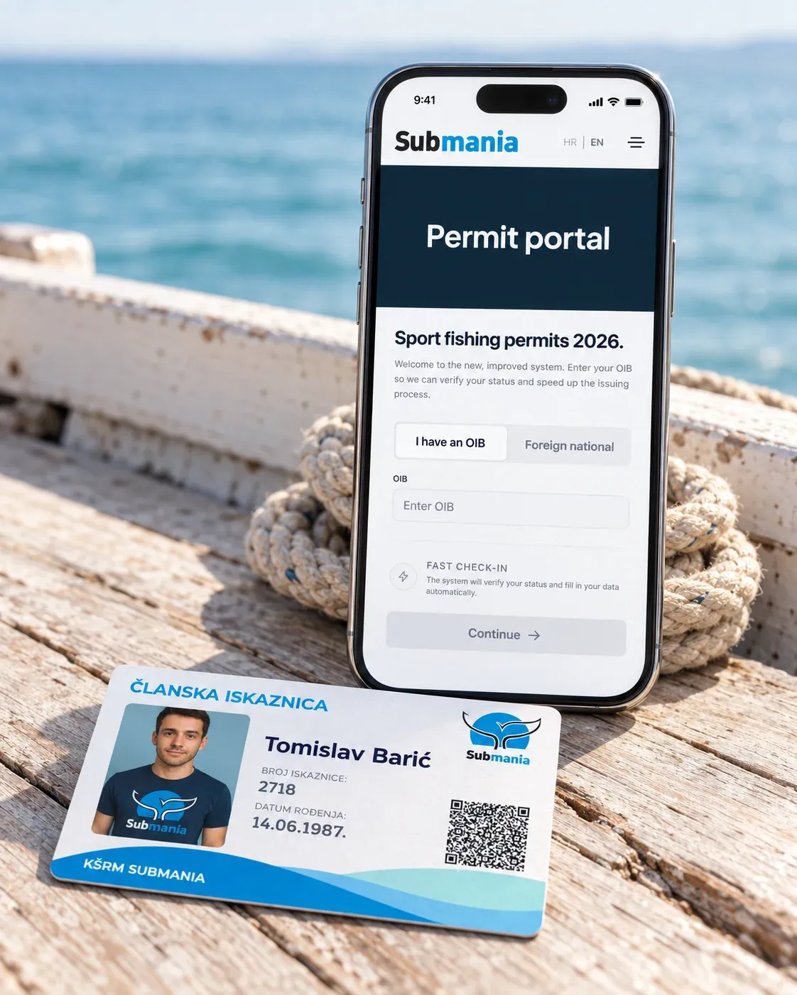 A phone stands on the deck of a small fishing boat, open on the Submania permit portal for 2026 sport fishing permits. In front of it lies a KŠRM Submania membership card marked as active.
